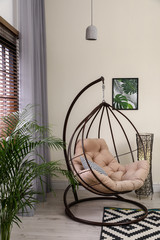 Comfortable swing chair with pillows in room interior