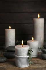 Composition with burning candles, spa stones and eucalyptus on wooden table, space for text