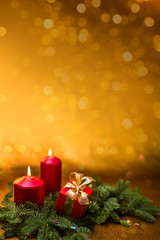 Gifts with bows, burning red candles and spruce branch on a golden background.