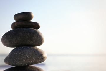 Stack of dark stones against blurred background, space for text. Zen concept