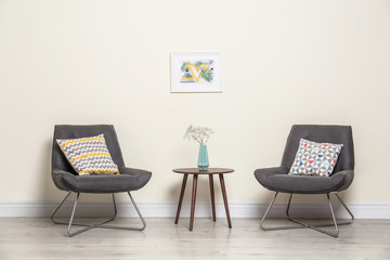 Fototapeta premium Room interior with modern chairs and table near light wall