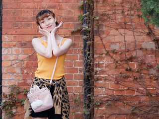 Portrait of happy Chinese girl in yellow halter top and short skirt posing and smiling with red...