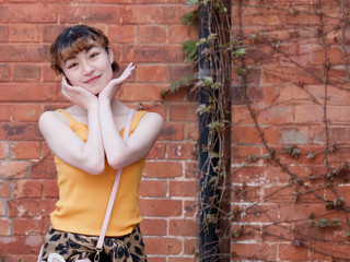 Portrait of happy Chinese girl in yellow halter top and short skirt posing and smiling with red...