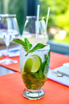 Mojito cocktail with lime and mint in a glass on the table in a sunny day