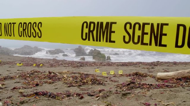 FOGGY BEACH CRIME SCENE, WITH POLICE TAPE AND EVIDENCE MARKERS.  4K, 10 BIT SLIDER SHOT.  NO PEOPLE.