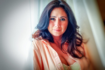 Portrait of a woman standing in front of window, silhoutted by curtains