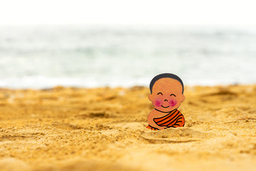 Little boy Buddhist, little Buddha, sitting on the sand on the beach . Rejoice and smiles in the Lotus position. Meditation and relaxation