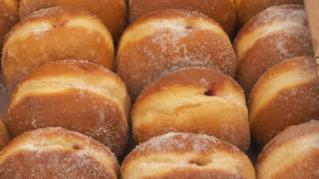 Rows of jam doughnuts on a stall.