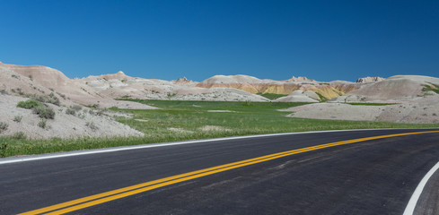 Highway running through arid yellow mound landscape