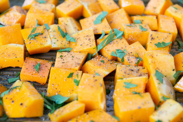 Cubed Butternut Squash on Sheet Pan covered in olive oil, pepper, salt, and parsley, raw vegetable in baking sheet