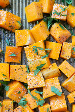 Cubed Butternut Squash On Sheet Pan Covered In Olive Oil, Pepper, Salt, And Parsley, Raw Vegetable In Baking Sheet