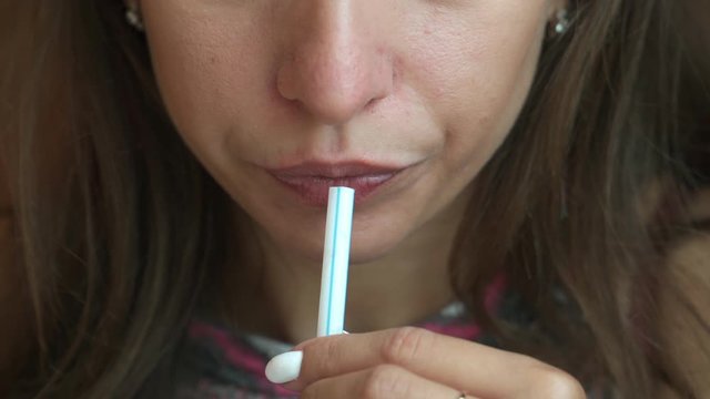 Close-up. A young girl with long hair drinks water from a plastic Straw.
