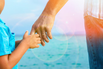 hands of happy parent and child at sea greece background