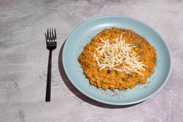 pumpkin peas risotto with parmesan topping on concrete table