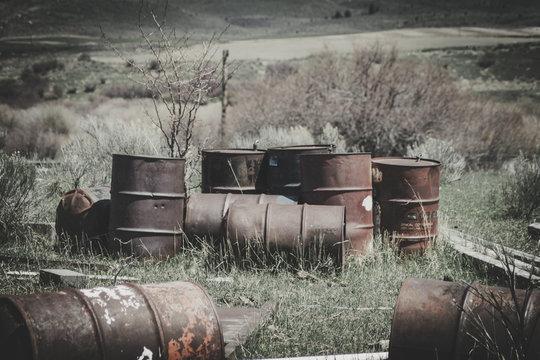 Old Rusty Steel Drum Barrels Sitting in a Field