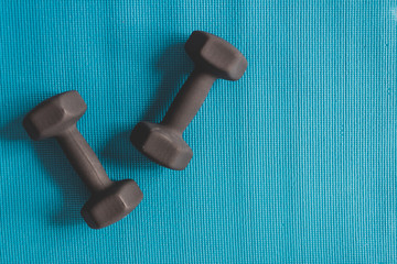 black set of dumbbells on blue yoga mat