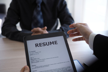 Executives are interviewing candidates and holding a tablet, opening the resume from the email that...