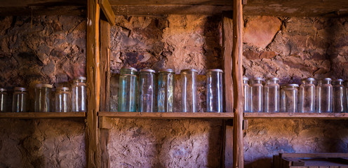 Jars on hand made wooden shelves against a stone wall