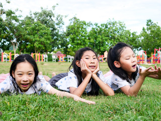 Happy Asian girls laying down on green grass outdoor together, lifestyle concept.