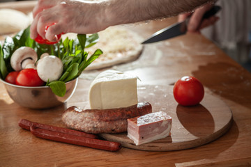  A man is preparing pizza. Close-up slices ingredients.