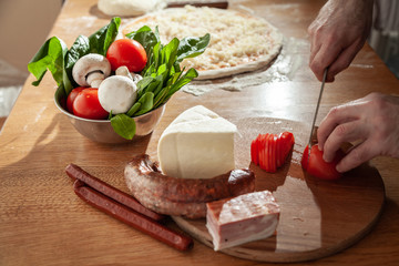  A man is preparing pizza. Close-up slices ingredients.