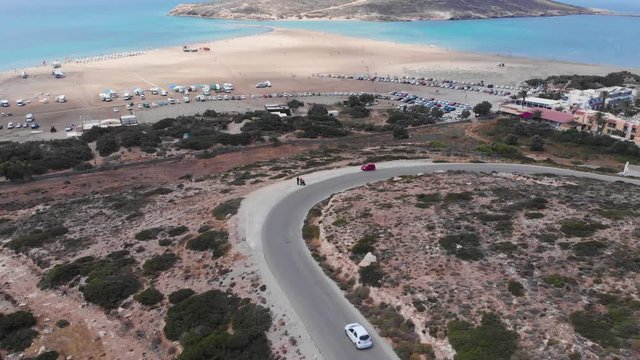 Aerial: Flying backwards above curvy road at Prasonisi Kite Beach, Rhodes
