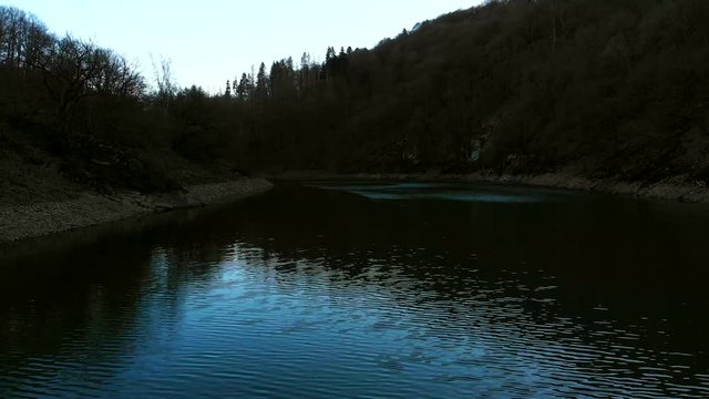 Flying low above the water at the foot of the mountain. 4K