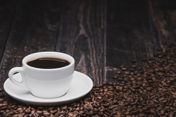 cup of coffee with beans on brown wooden background