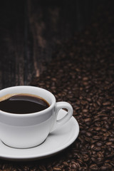 close up cup of coffee with beans on brown wooden background