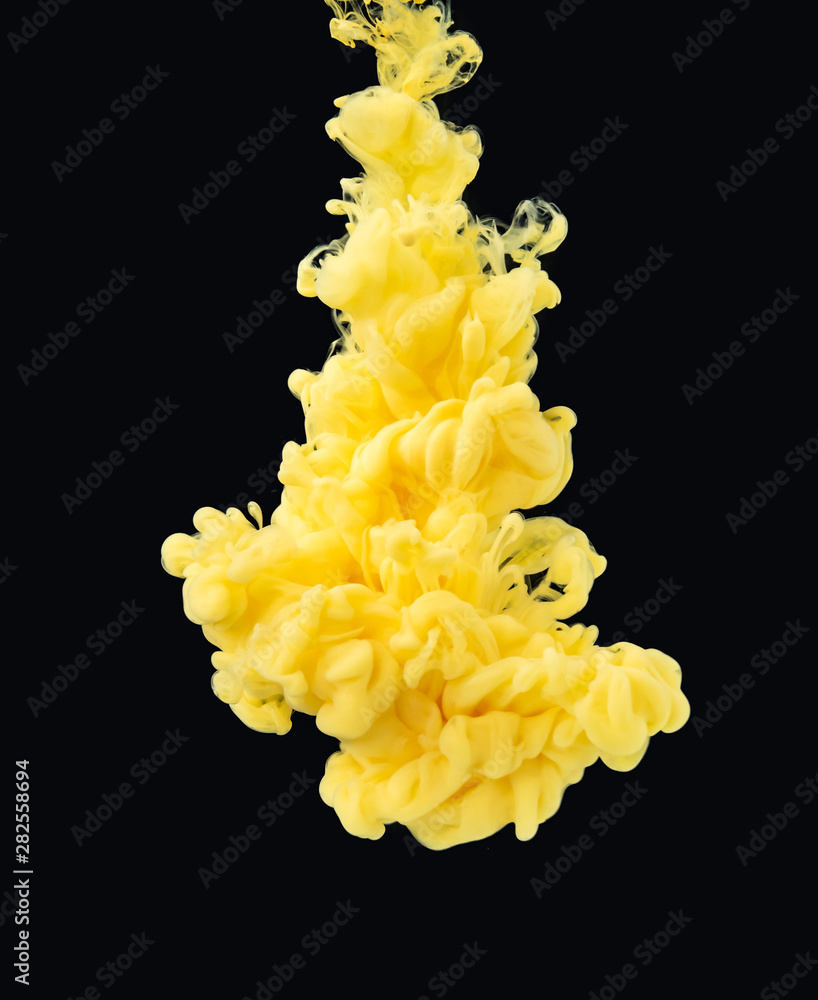 Poster drop of yellow paint photographed while swirling under water, isolated on black background, close up