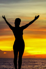 Fototapeta premium strong confidence woman open arms under the sunrise at seaside