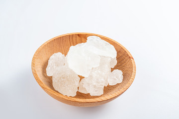 Polycrystalline crystal sugar filled with a wooden dish on a white background