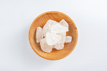 Polycrystalline crystal sugar filled with a wooden dish on a white background