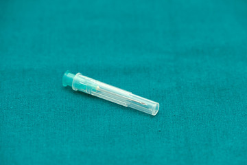 Injection needle with cover isolated on surgical green drape