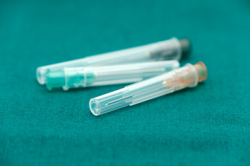 Three color of injection needle with cover isolated on surgical green drape