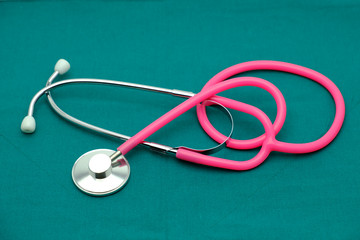 Pink stethoscope isolated on surgical  green drape background