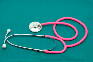 Pink stethoscope isolated on surgical  green drape background
