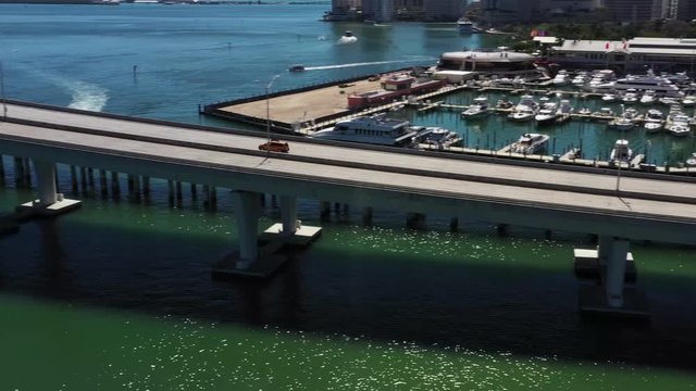 Taxicab drives over bridge (Miami port) drone pan and tracks cab