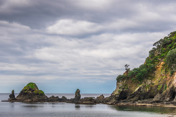 rock and sea under cloudy sky