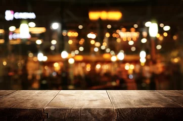 Schilderijen op glas achtergrond Afbeelding van houten tafel voor abstracte wazige restaurantverlichting © tomertu