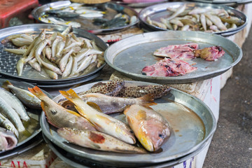 Fresh fish fillets, cut into pieces, put on a plastic basket in the market.