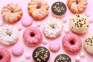Various types of donuts on pink background.