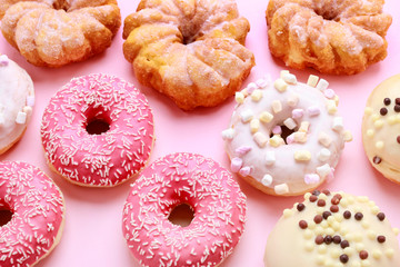 Various types of donuts on pink background.