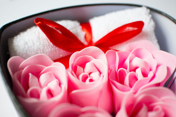 white towel with red bow and rose soap on white background, body care and cleanliness concept