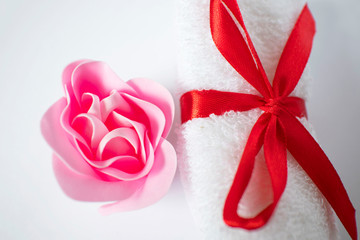 white towel with red bow and rose soap on white background, body care and cleanliness concept