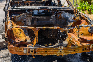 Fototapeta premium Burned car parked on the street, close-up. Abandoned burnt down car after an explosion, ready to be scrapped
