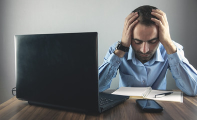 Caucasian stressed businessman sitting and touching head in office.