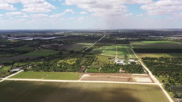 An Aerial view by drone over the farm of the Redlands Florida. Two separate views from the low pass over newly planted crops to a high view with the clouded skyline.