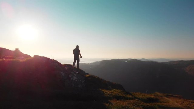 Man walking at the end of a cliff, photographing the beautiful landscape - Aerial 4K