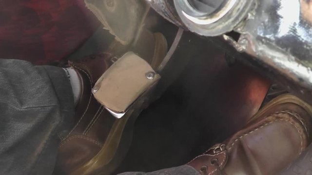 Inside view of the cockpit of a typical and classic vintage Cuban Taxi transporting tourists through Havana. Close-up of the driver's feet and the pedals while driving.
